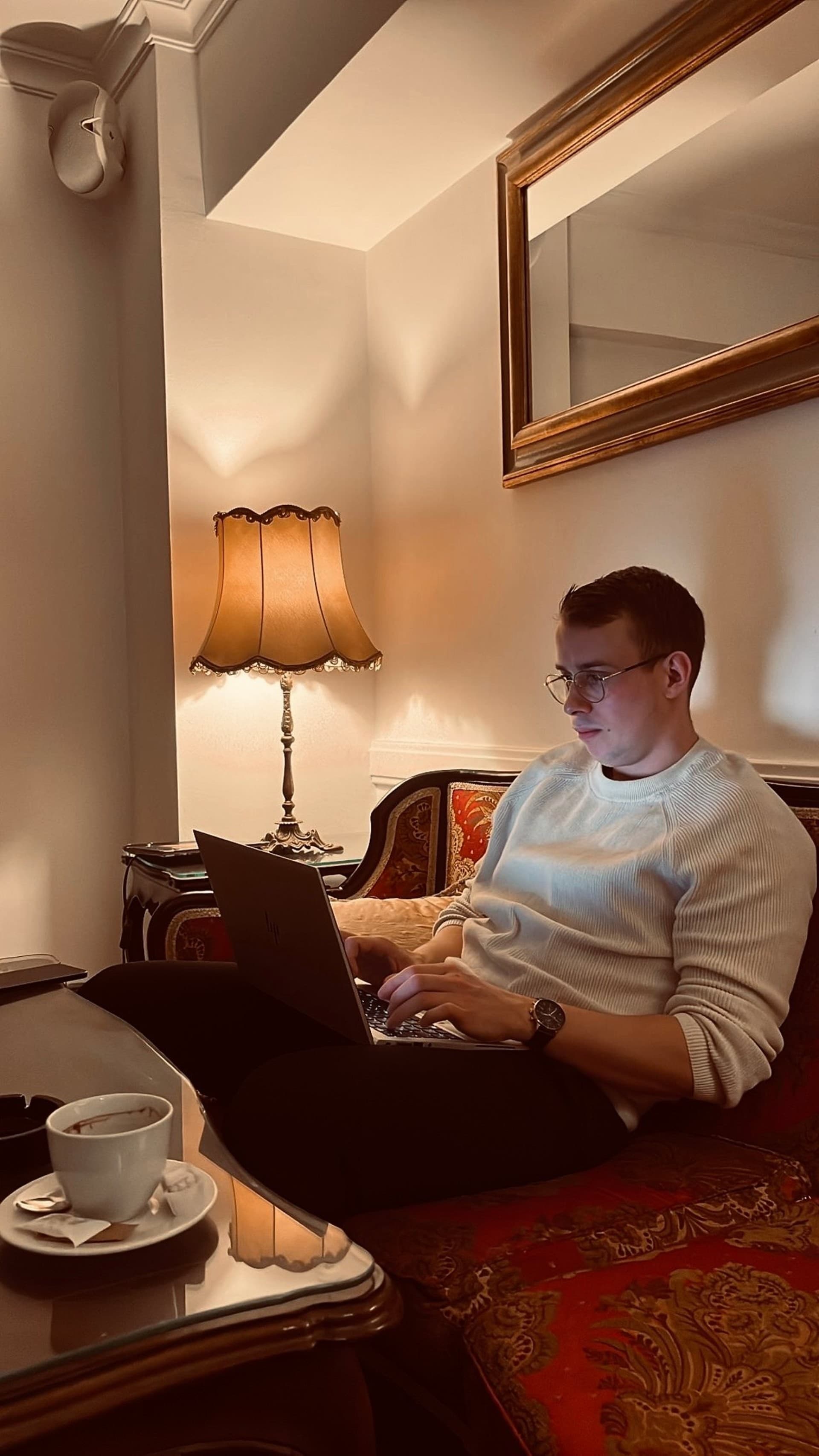 Christopher Krassnig with laptop on a red ornate couch